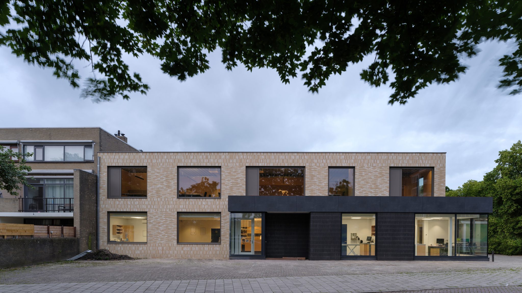 Corner building with glass corner aluminum window frames on ground floor extension. Light colored brick on CLT wood wall and new main entrance to veterinary clinic. Veterinary clinic design for Anicure ‘t Leidse Land in Leiderdorp, designed and built by MOST Architecture, Rotterdam