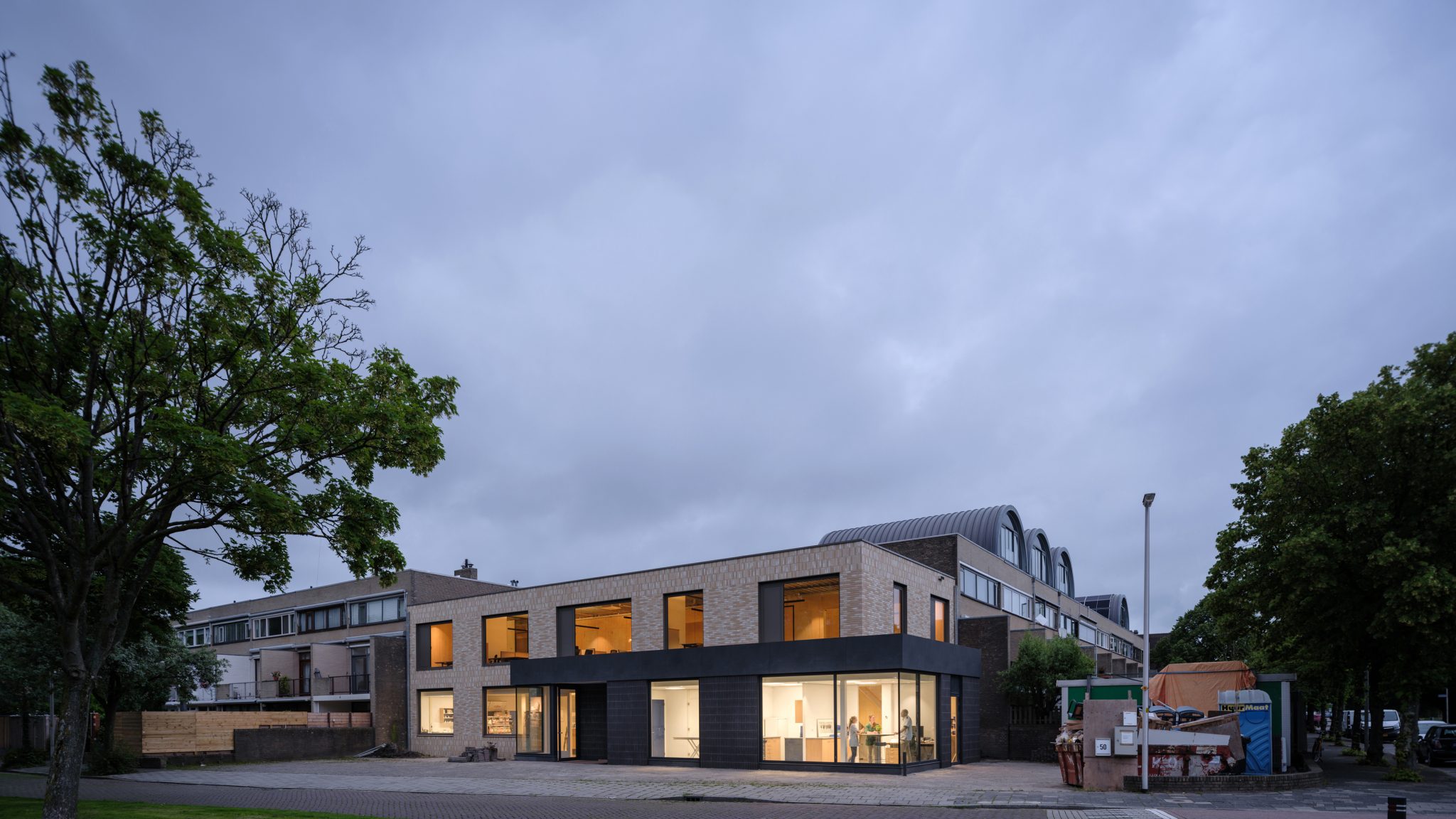 Corner building with glass corner aluminum window frames on ground floor extension. Light colored brick on CLT wood wall and new entrance to veterinary clinic. Veterinary clinic design for Anicure ‘t Leidse Land in Leiderdorp, designed and built by MOST Architecture, Rotterdam