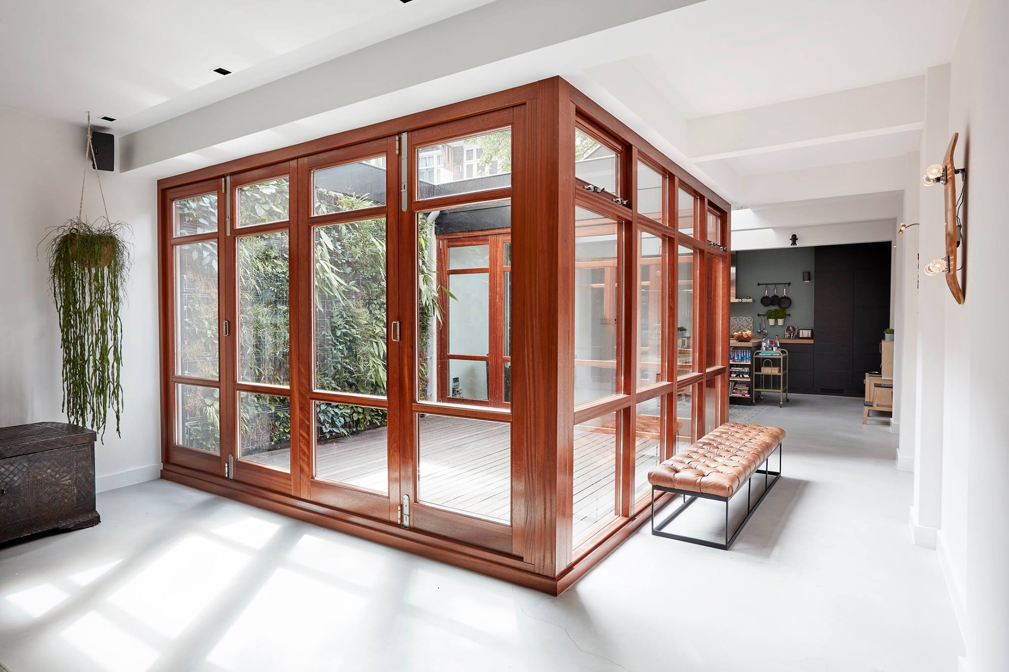 Patio with planted green wall brings in sunlight and daylight deep into a bespoke residential interior design in Amsterdam near the Vondelpark. Filled with vintage furniture and skateboard art, raw concrete and white plastered walls is designed and built by MOST Architecture, Rotterdam