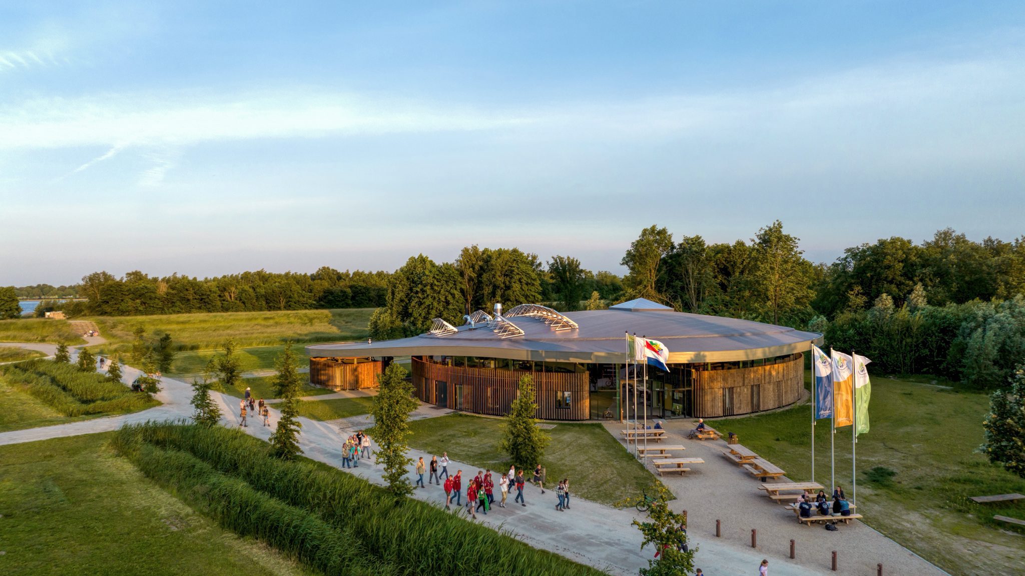 Entrance view with people passing by the Adventurehouse on Socutinglandgoed Zeewolde a design by MOST Architecture