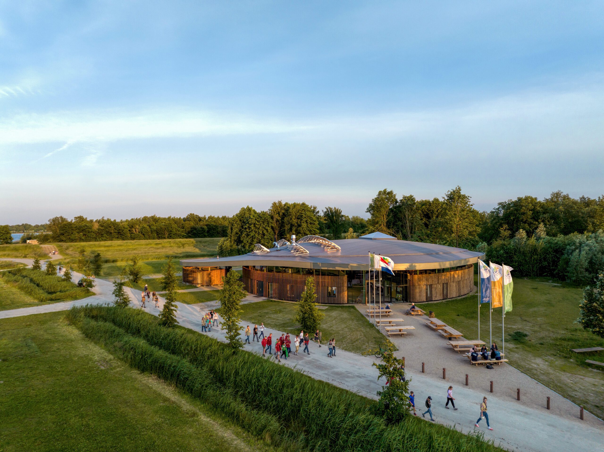 Entrance view with people passing by the Adventurehouse on Socutinglandgoed Zeewolde a design by MOST Architecture